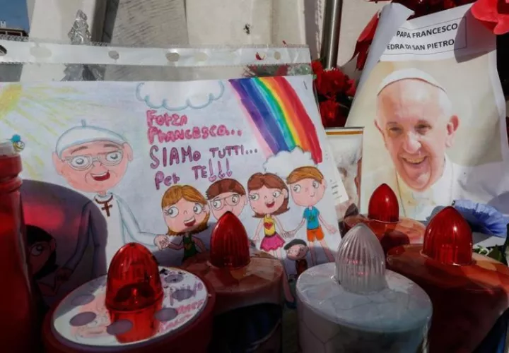 Un dibujo y una fotografía del papa Francisco bajo la estatua de Juan Pablo II. Foto: EFE