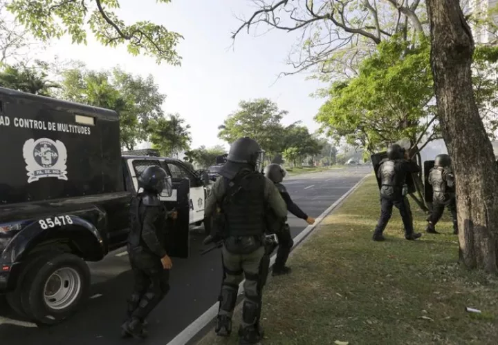 Policías antidisturbios vigilan un área durante protestas. Foto: EFE