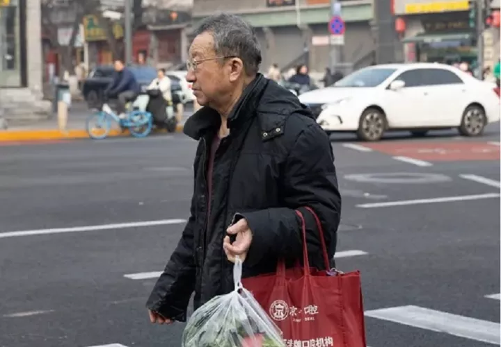 Una persona con bolsas de la compra camina por una calle transitada en Pekín, China. EFE/EPA/Jessica Lee