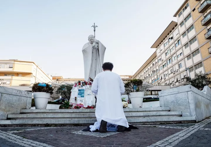 Una persona reza cerca de la estatua de Juan Pablo II frente al Hospital Agostino Gemelli, donde el Papa Francisco continúa su tratamiento. Foto: EFE