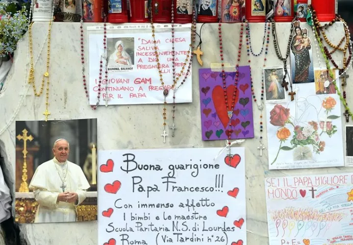 Velas, rosarios y mensajes de apoyo al papa Francisco se exhiben en la estatua del papa Juan Pablo II junto al Hospital Universitario Gemelli, donde está hospitalizado. Foto: EFE