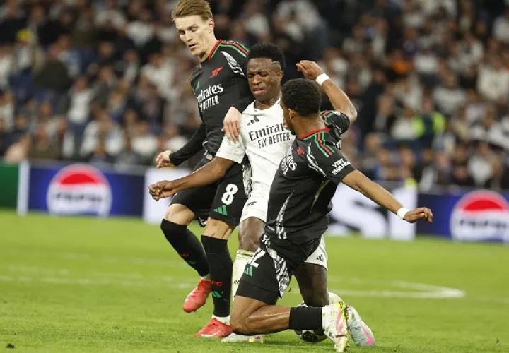 El brasileño del Real Madrid, Vinicius (cent.), disputa el balón ante los jugadores del Arsenal, Martín Odegaard (izq) y Jurrien Maduro, Foto: EFE