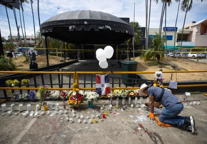 Un hombre enciende velas en la entrada de la discoteca Jet Set. Foto: EFE