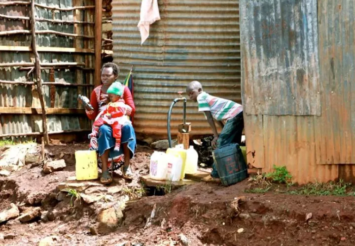 Una mujer y sus dos hijos recogen agua en bidones en uno de los distritos de Kibera (Kenia). Foto: EFE