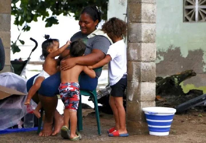 La venezolana Marielbis Eloina Campos, de 33 años, jugando con sus hijos, en el pueblo pesquero de Miramar en el Caribe panameño. EFE/ Moncho Torres