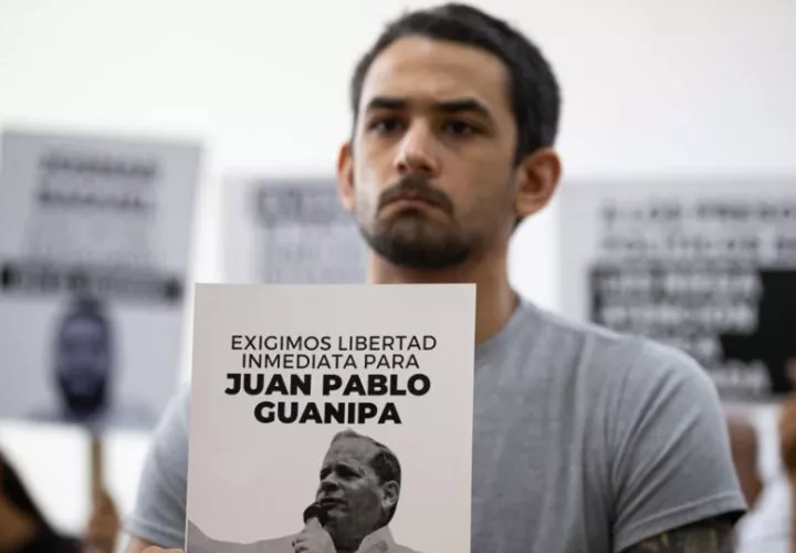 Ramón Guanipa sostiene un cartel de su padre detenido, Pedro Guanipa. Foto: EFE