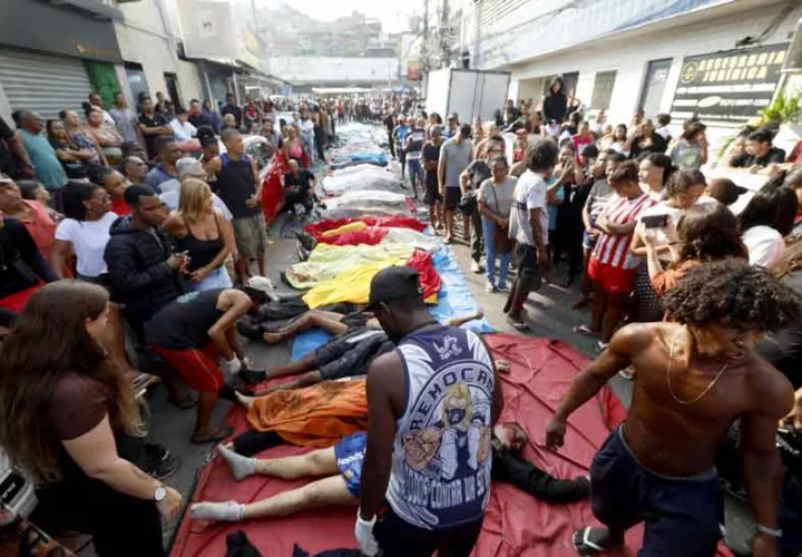 Personas observan cuerpos sin vida en una calle este miércoles, en Río de Janeiro. Foto EFE