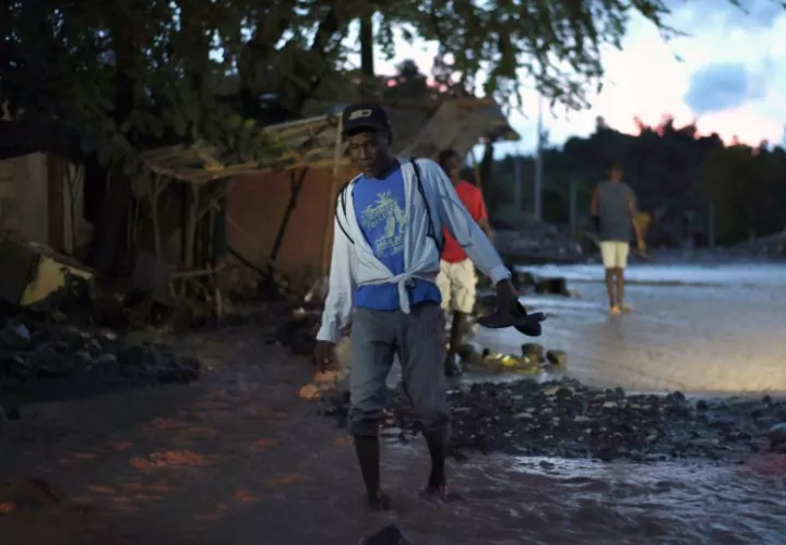 Una persona camina sobre el lodo tras la creciente del río La Digue. Foto: EFE