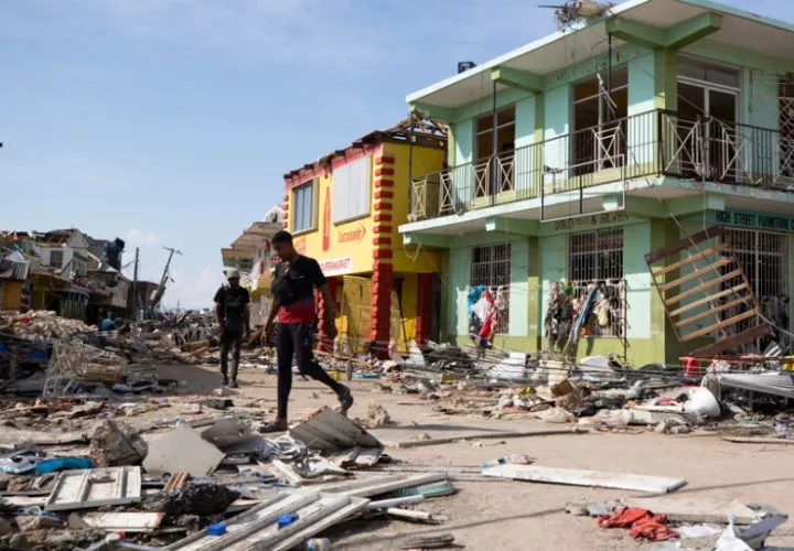 Personas caminan por una calle destruida por el paso del huracán Melissa, en Black River (Jamaica). Foto: EFE