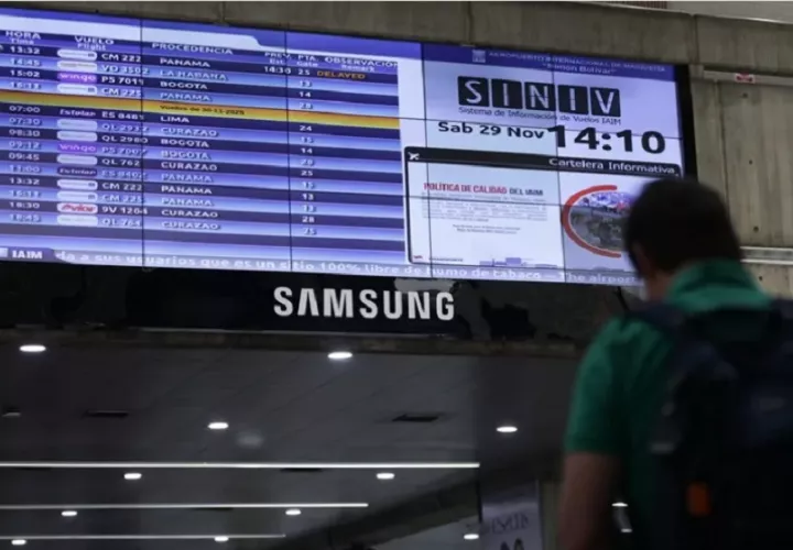 Fotografía de una persona caminando junto a una pantalla con la programación de vuelos, en el Aeropuerto Internacional Simón Bolívar, en Maiquetía (Venezuela). Foto: EFE/ Ronald Peña R.