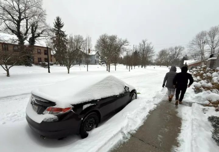 Dos personas caminan al lado de una calle afectada por la nieve en la ciudad de Hudson, Ohio (EE.UU.). Foto: EFE