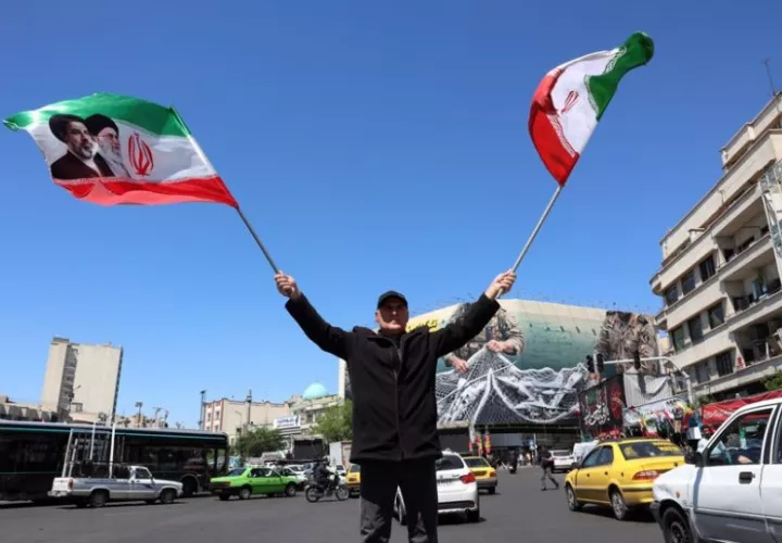Un hombre ondea banderas iraníes en Teherán. Foto: EFE