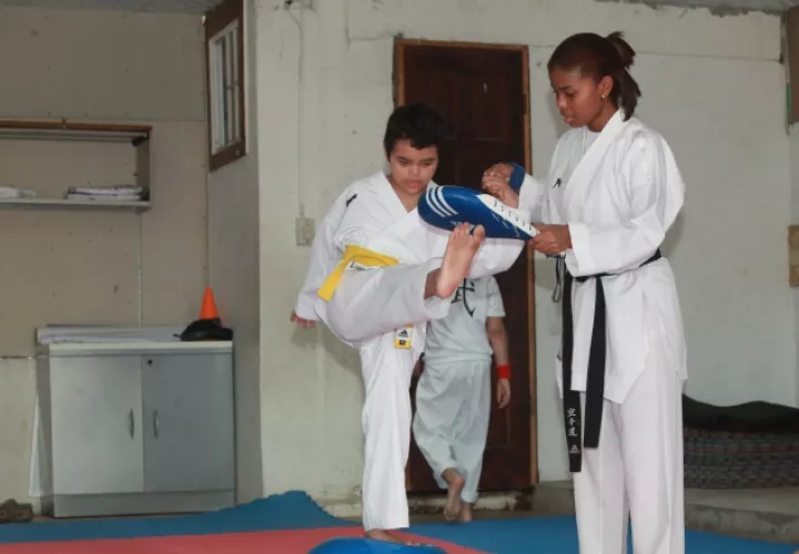El niño Ian Sáez, asistido por uno de sus maestros, realiza una patada durante un entrenamiento en la academia de Don Bosco. /Foto Anayansi Gamez