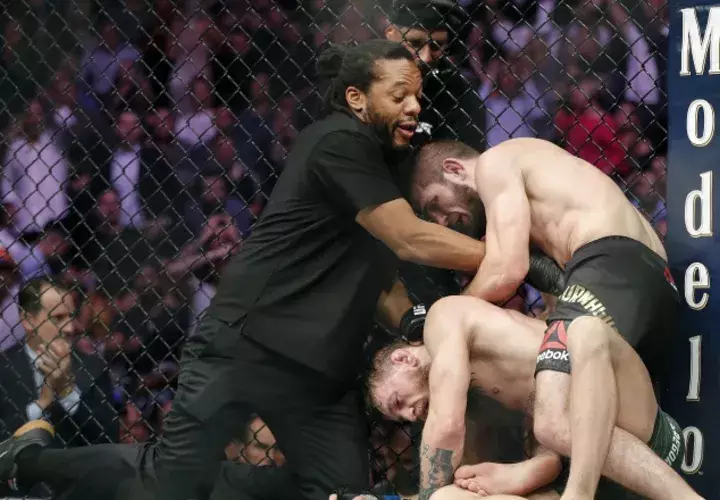 Khabib Nurmagomedov somete a  Conor McGregor (c) ante la mirada del árbitro Herb Dean (izq.). /Foto AP