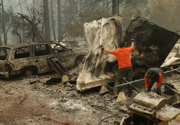 Un socorrista busca restos humanos en un vehículo  calcinado en un parque de autos en California. AP