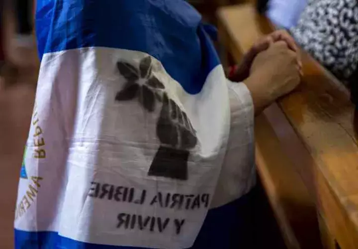 Una joven con una bandera de Nicaragua en la espalda participa de una misa para pedir por la liberación de los presos políticos. EFE