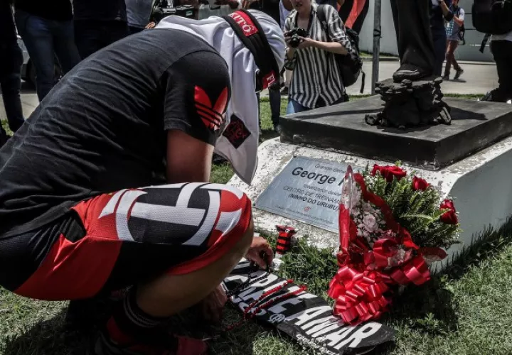 Un aficionado pone flores en homenaje a las víctimas del incendio registrado ayer. EFE