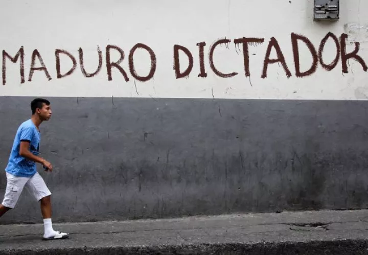 Una persona camina frente a una pared pintada contra el presidente de Venezuela, Nicolás Maduro,  en el centro de la ciudad de Caracas. EFE