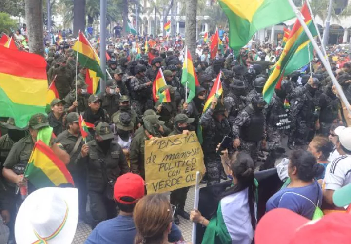 Un grupo de policías ondea la bandera tricolor de Bolivia mientras se repliega a una comisaría. FOTO/EFE