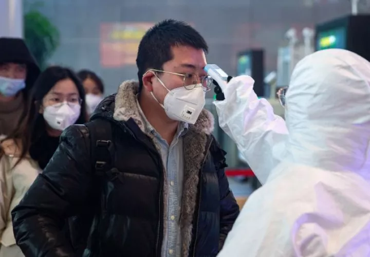 Personal médico chequea la temperatura de una persona en Nanjing, China como medidas de prevención contra el coronavirus. Foto EFE
