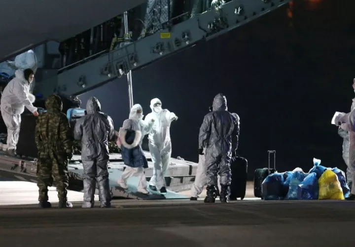 Especialistas bioquímicos recibieron ayer  en el aeropuerto de Ankara, a ciudadanos turcos evacuados de Wuhan, China. EFE.
