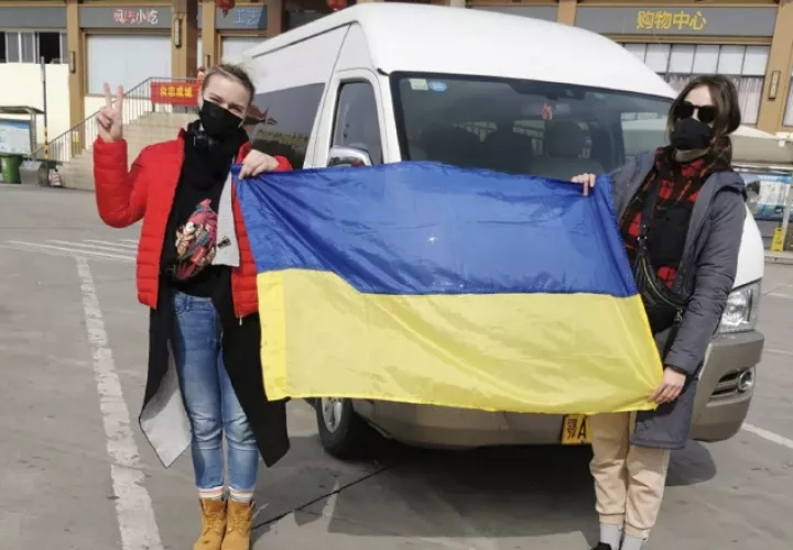 Los pasajeros ucranianos sostienen la bandera de su país  antes de abordar un avión fletado. FOTO/AP