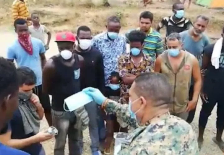 Un agente del Senafront entrega mascarillas a migrantes. Foto EFE