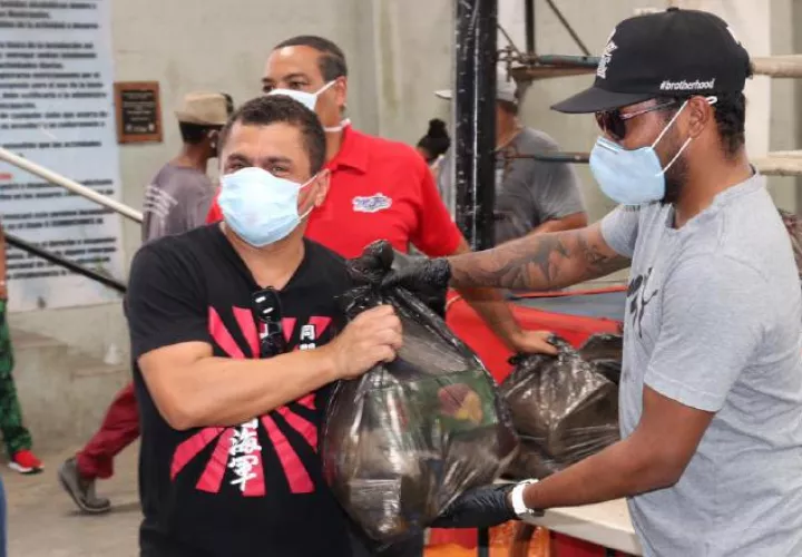 Anselmo "Chemito" Moreno (der.) entrega bolsas de comidas. Foto: Cortesía