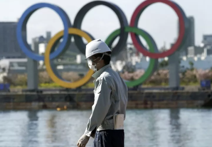 Un hombre trabaja con los anillos olímpicos fe fondo en el distrito de Odaiba en Tokio. Foto:AP