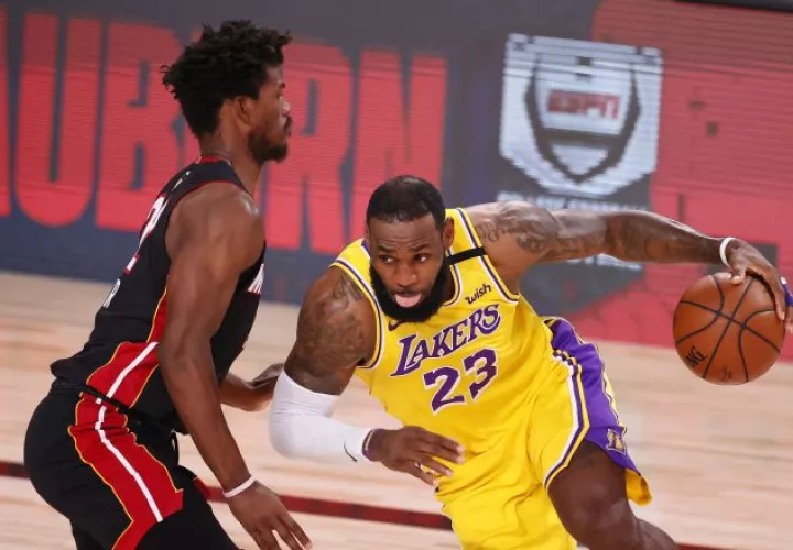 El alero de Lakers LeBron James (23) con el balón ante el alero del Miami Heat Jimmy Butler. Foto:EFE 