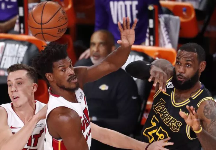 LeBron James realiza un pase de balón, ante la marca  Jimmy Butler de los Heat.  Foto:EFE