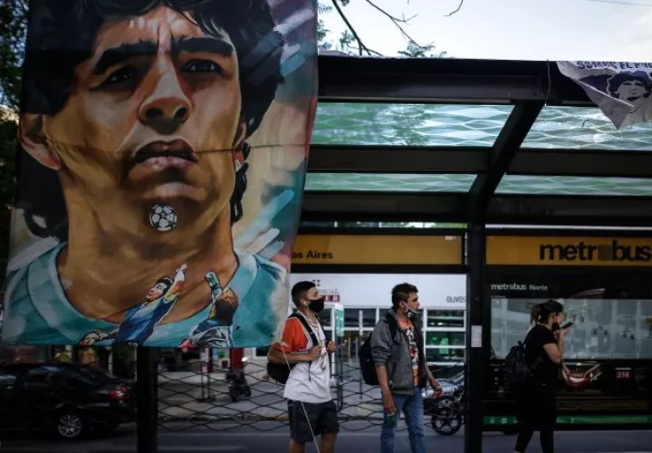 Carteles y banderas alusivas al exfutbolista y entrenador argentino Diego Armando Maradona cuelgan en una estación de bus cercana a la clínica Olivos.  Foto:EFE