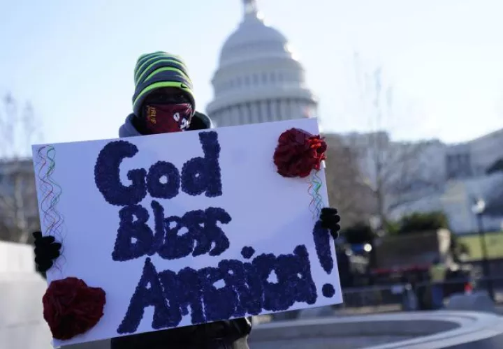 Un hombre sostiene un cartel que dice 'Dios bendiga a América' fuera del Capitolio de los Estados Unidos, en Washington. Foto:EFE