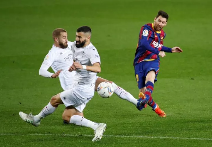 El delantero argentino del Barcelona, Leo Messi (der.) reamata el balón ante los defensores del Huesca. Foto:EFE
