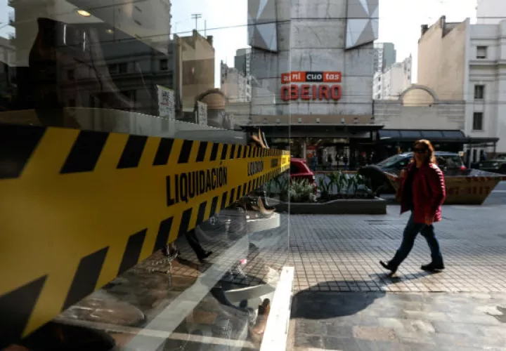 Una mujer pasa frente a un negocio con aviso de liquidación, en Buenos Aires (Argentina). Foto: EFE.