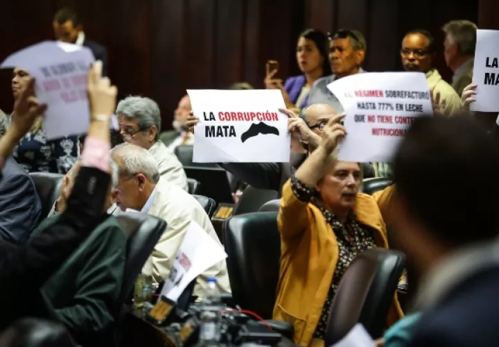 Diputados de la Asamblea Nacional levantan carteles denunciando corrupción en el Gobierno de Nicolás Maduro, en el Palacio Federal Legislativo en Caracas. FOTO/EFE