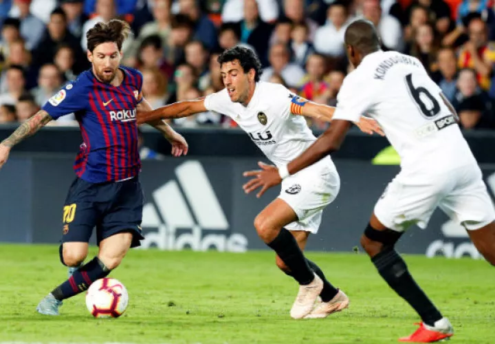 El centrocampista del Valencia CF Dani Parejo (c), lucha por el balón ante el delantero argentino del FC Barcelona, Lionel Messi (i). Foto:EFE