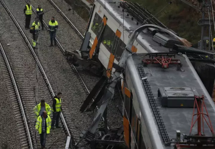 Bomberos y trabajadores de emergencia están parados junto a los vagones descarrilados del tren cerca de Barcelona. EFE
