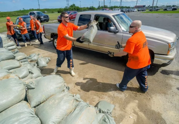 Los trabajadores internos de la Oficina del Alguacil de la Parroquia de St. Bernard trasladan sacos de arena gratuitos para los residentes de Chalmette. FOTO/AP