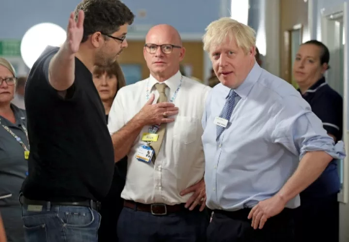 Omar Salem, cuya hija está siendo tratada, en el pabellón de niños Acorn, hace gestos mientras habla con el primer ministro británico, Boris Johnson, durante su visita al Hospital Universitario Whipps Cross en Leytonstone, este de Londres. FOTO/AP