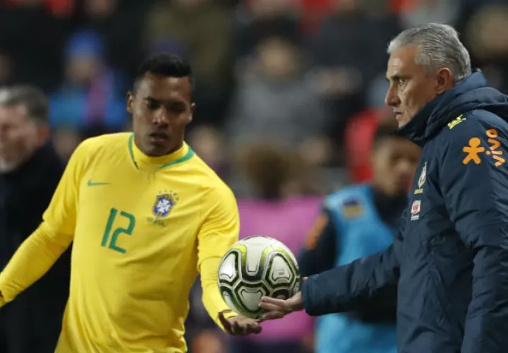 Tite entrega el balón a un jugador de la selección de Brasil. Foto AP