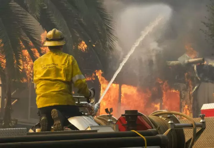 Un bombero echa agua a una casa incendiada en Malibú. Foto: AP.