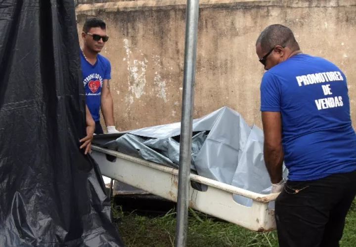 Dos hombre retiran uno de los cuerpos de las víctimas de la masacre en el Centro de Recuperación Regional de Altamira, en el IML (Instituto Legal de Medicina), en Altamira. FOTO/EFE