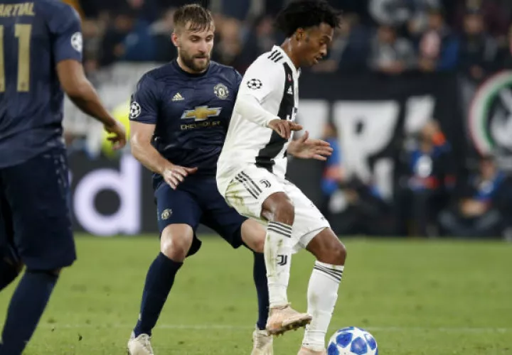 Juan Guillermo Cuadrado (der.) protege el balón ante la marca de Luke Shaw del United. Foto:AP