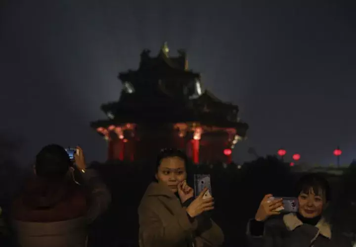  los visitantes toman fotos de la Ciudad Prohibida iluminada con luces para el Festival de los Faroles en Beijing. FOTO/AP