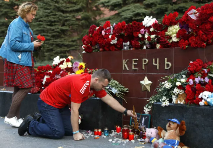 La gente trae flores y velas para honrar a las víctimas del ataque del miércoles a una escuela vocacional en Kerch, Crimea. AP