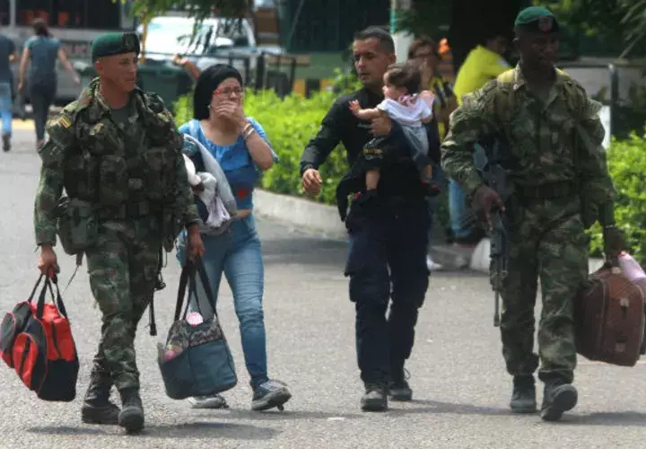 Soldados colombianos acompañan a un policía venezolano (c-d), que carga a su hija, y a su esposa (c-i), luego de desertar, este miércoles en el puente Simón Bolívar, en Cúcuta (Colombia). Foto: EFE.