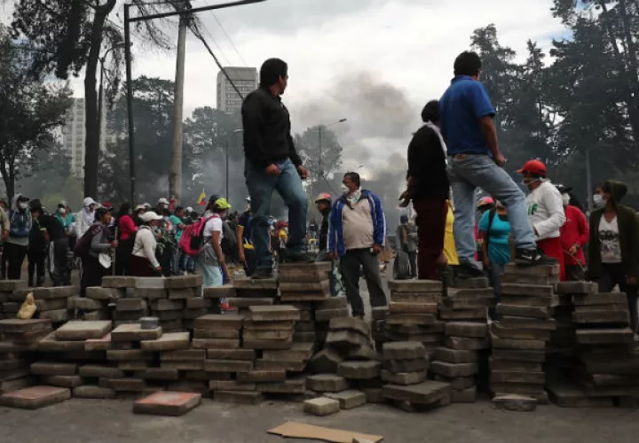 Manifestantes tras una barricada de piedras que bloquea una calle este sábado, en Quito. Foto: EFE.