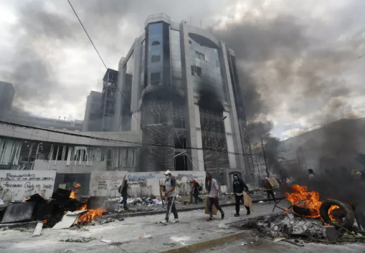 Manifestantes tras una barricada de piedras que bloquea una calle este sábado, en Quito. Foto: EFE.