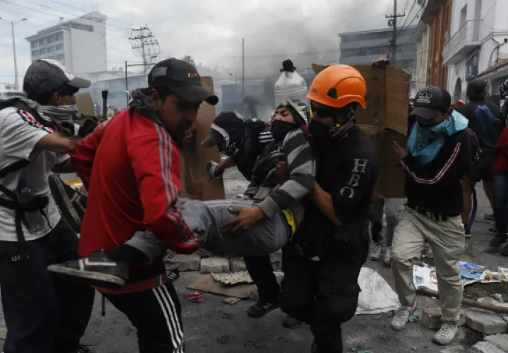 Manifestantes tras una barricada de piedras que bloquea una calle este sábado, en Quito. Foto: EFE.